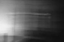 Image 1. An abandoned living room with furniture still there. There is no light but one can see traces of different people who have used this room. There are signs of sleeping, eating, smoking, and drinking.