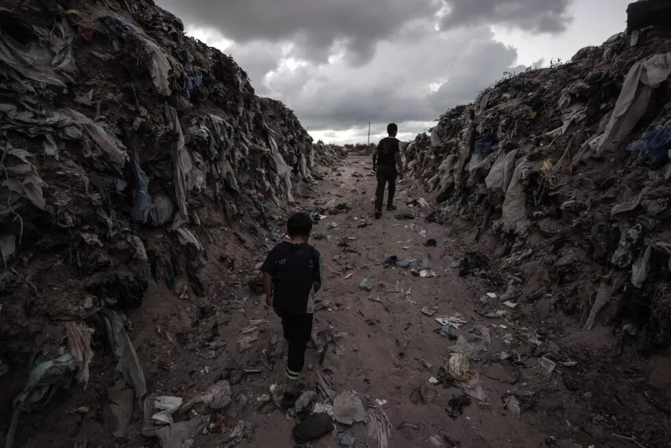 Children walking through piles of garbage near theor homes in Khan Younis